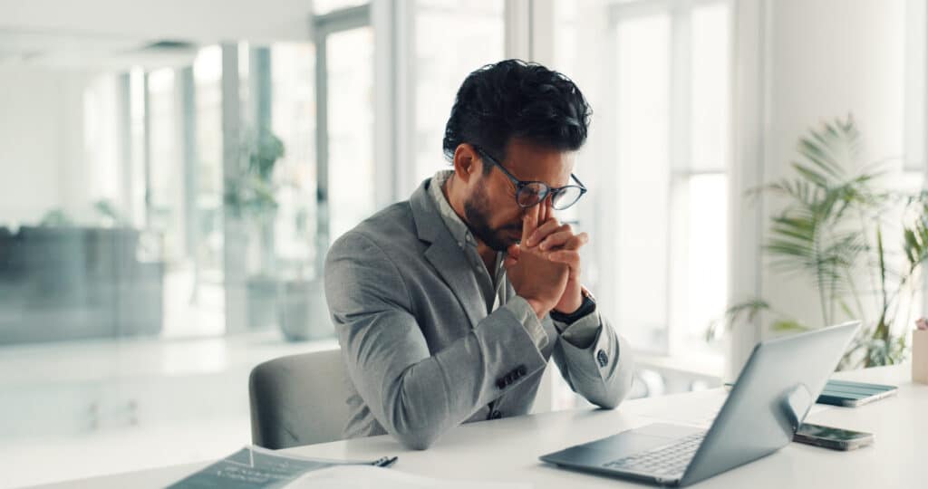 Gestresster Mann im Büro sitzt am Schreibtisch